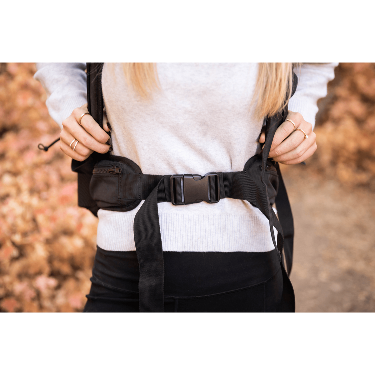Close-up of a person fastening the padded lap belt on the Knavigate dog carrier backpack
