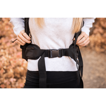 Close-up of a person fastening the padded lap belt on the Knavigate dog carrier backpack