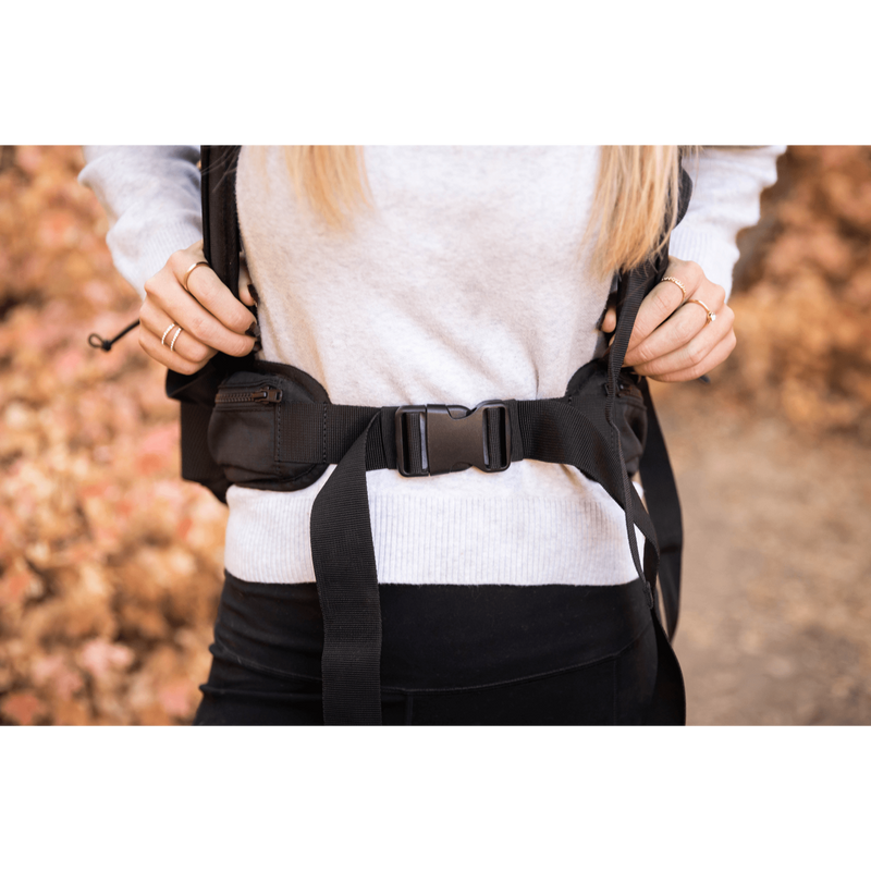 Close-up of a person fastening the padded lap belt on the Knavigate dog carrier backpack